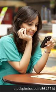 Young woman reading text message on cell phone