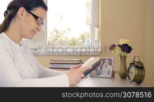 Young woman reading the Bible and beginning to pray in her devotional time at home. Dolly shot. 4K footage at 60fps.