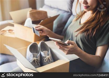 young woman received online shopping parcel opening boxes and buying fashion items by using credit card. young woman received online shopping parcel opening boxes