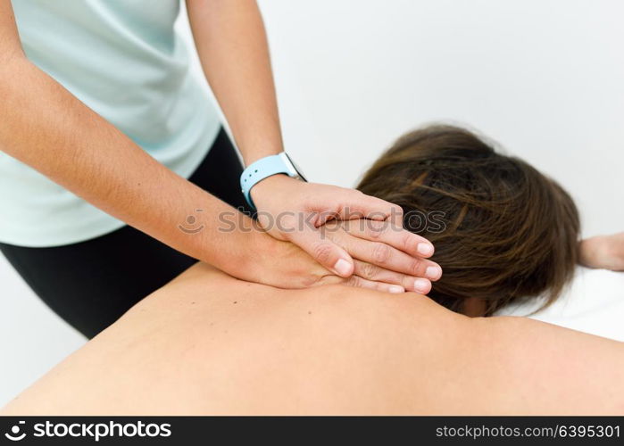 Young woman receiving a back massage in a spa center. Female patient is receiving treatment by professional therapist.