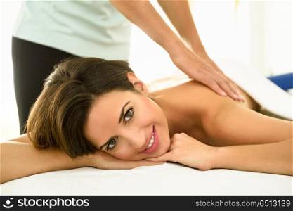 Young woman receiving a back massage in a spa center.. Young woman receiving a back massage in a spa center. Female patient is receiving treatment by professional therapist.