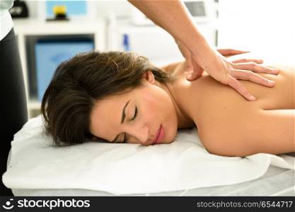 Young woman receiving a back massage in a spa center.. Young woman receiving a back massage in a spa center. Female patient is receiving treatment by professional therapist.