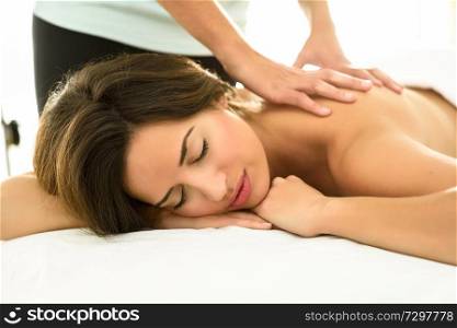 Young woman receiving a back massage in a spa center. Female patient is receiving treatment by professional therapist.. Young woman receiving a back massage in a spa center.