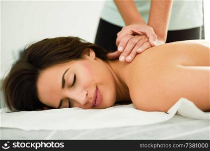 Young woman receiving a back massage in a spa center. Female patient is receiving treatment by professional therapist.. Young woman receiving a back massage in a spa center.