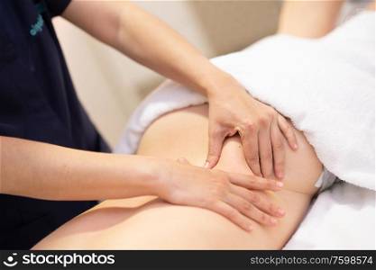 Young woman receiving a back massage in a spa center. Female patient is receiving treatment by professional therapist.. Young woman receiving a back massage in a spa center