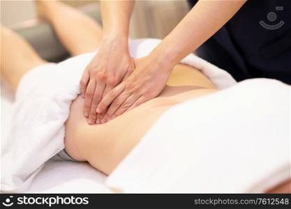 Young woman receiving a back massage in a spa center. Female patient is receiving treatment by professional therapist.. Young woman receiving a back massage in a spa center