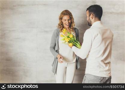 Young woman receiving a gift of  yellow tulips from her husband or partner smiling at him
