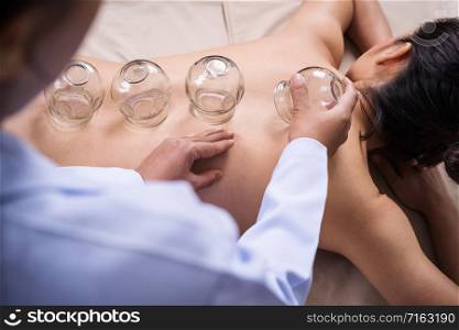 young woman receiving cupping treatment on back with doctor