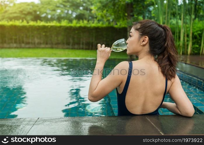 young woman relax in swimming pool and drinking wine