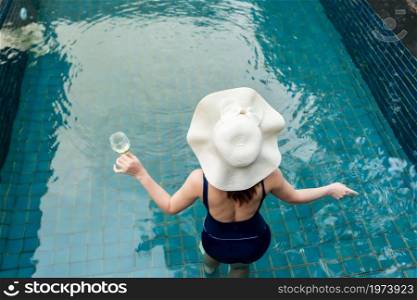 young woman relax in swimming pool and drinking wine