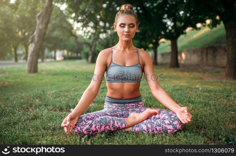 Young woman relax in yoga pose on the grass. Morning yogi meditation
