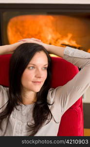 Young woman relax on red armchair by home fireplace