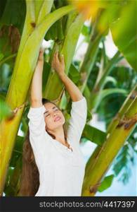 Young woman relaxing among tropical palms