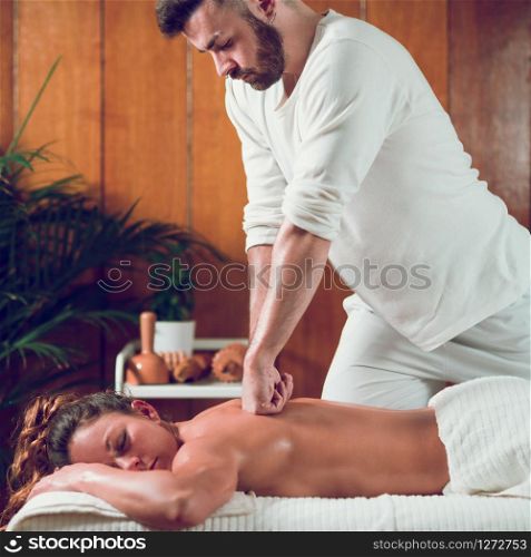 Young woman relaxing and having back massage in spa salon