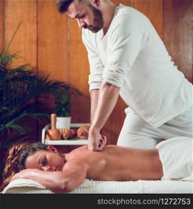 Young woman relaxing and having back massage in spa salon