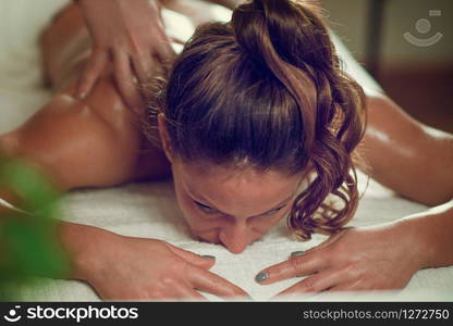 Young woman relaxing and having relaxing shoulders and neck massage massage in spa salon