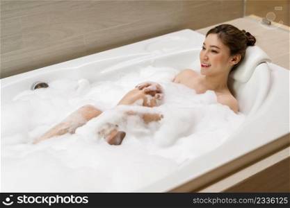 young woman relaxing and takes bubble bath in bathtub with foam