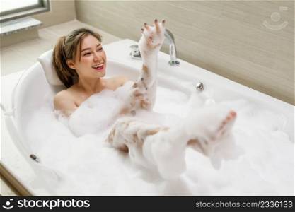 young woman relaxing and takes bubble bath in bathtub with foam