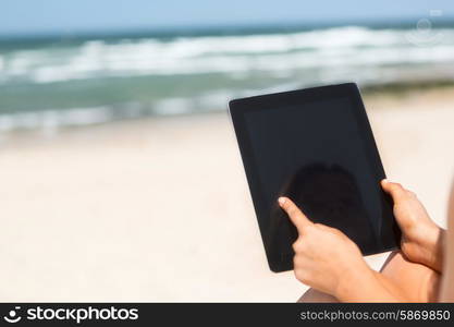 Young woman relaxing at the beach with a tablet computer