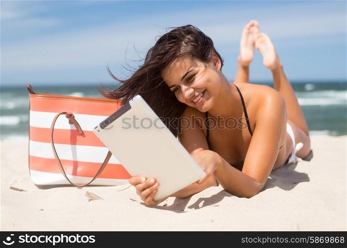 Young woman relaxing at the beach with a tablet computer