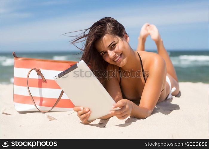 Young woman relaxing at the beach with a tablet computer