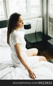 Young woman relaxing in a white bed in the morning