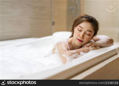 young woman relaxing in bathtube with eyes closed in bathroom