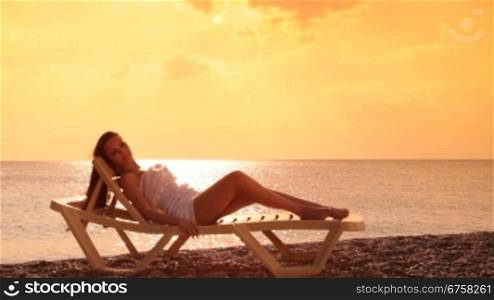 Young woman relaxing in the chaise lounge on a resort