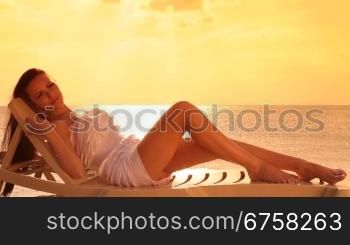 Young woman relaxing in the chaise lounge on a resort