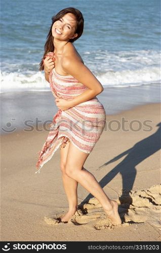Young Woman Relaxing On Beach Wearing Wrap