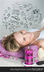 Young woman relaxing on massage table in health spa with burning candles and petals around her. Her dreams are sketched overhead