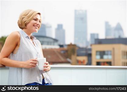 Young Woman Relaxing On Roof Terrace With Cup Of Coffee