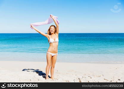 Young woman relaxing on the beach. Portrait of young pretty woman in white bikini relaxing on sandy beach