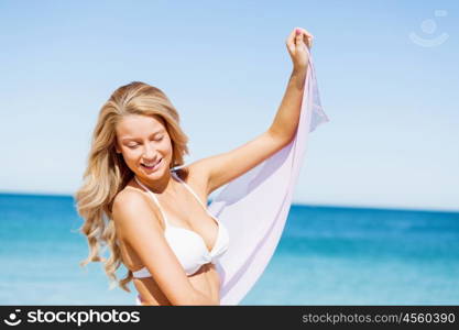 Young woman relaxing on the beach. Portrait of young pretty woman in white bikini relaxing on sandy beach