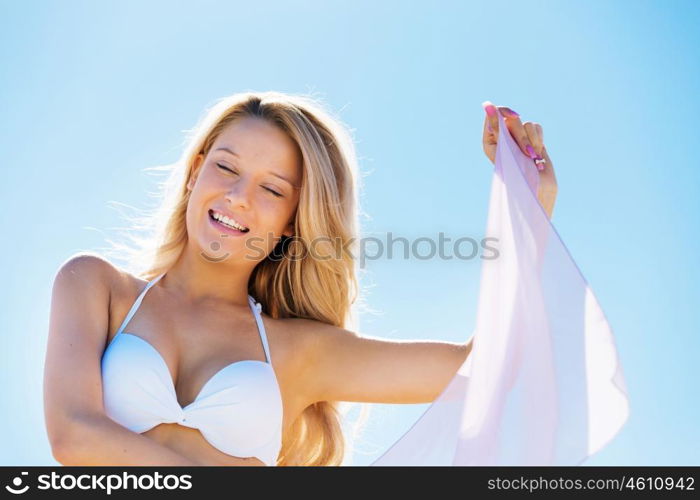 Young woman relaxing on the beach. Portrait of young pretty woman in white bikini relaxing on sandy beach