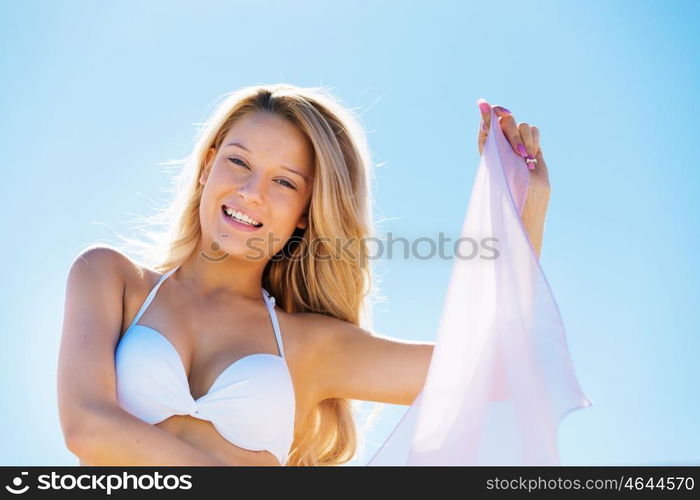 Young woman relaxing on the beach. Portrait of young pretty woman in white bikini relaxing on sandy beach