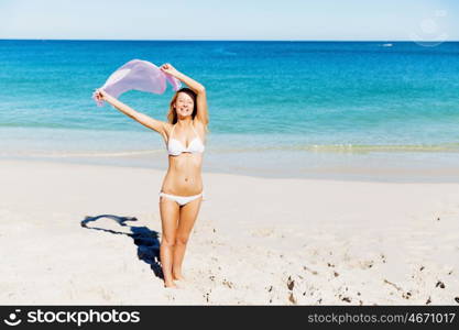 Young woman relaxing on the beach. Portrait of young pretty woman in white bikini relaxing on sandy beach