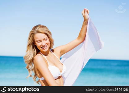 Young woman relaxing on the beach. Portrait of young pretty woman in white bikini relaxing on sandy beach