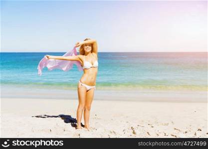 Young woman relaxing on the beach. Portrait of young pretty woman in white bikini relaxing on sandy beach