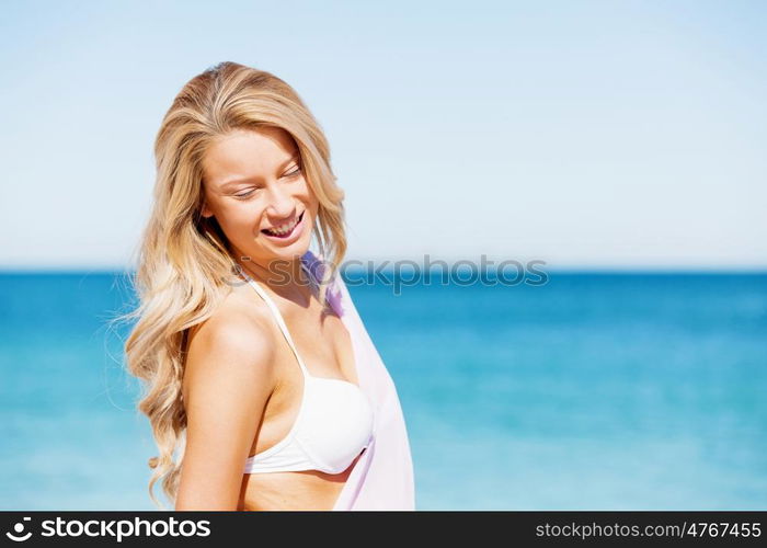 Young woman relaxing on the beach. Portrait of young pretty woman in white bikini relaxing on sandy beach