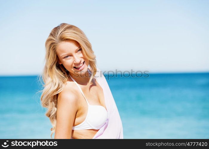 Young woman relaxing on the beach. Portrait of young pretty woman in white bikini relaxing on sandy beach