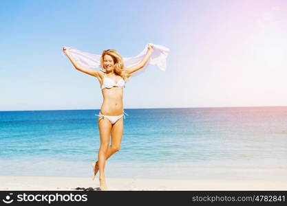 Young woman relaxing on the beach. Portrait of young pretty woman in white bikini relaxing on sandy beach