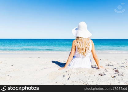 Young woman relaxing on the beach. Portrait of young pretty woman in white relaxing on sandy beach