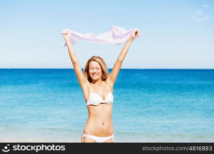 Young woman relaxing on the beach. Portrait of young pretty woman in white bikini relaxing on sandy beach