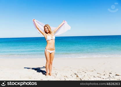 Young woman relaxing on the beach. Portrait of young pretty woman in white bikini relaxing on sandy beach