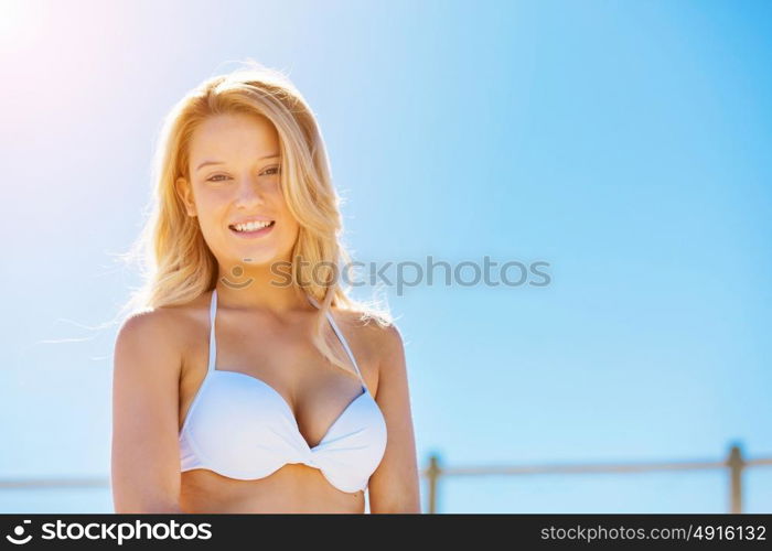 Young woman relaxing on the beach. Portrait of young pretty woman in white bikini relaxing on sandy beach