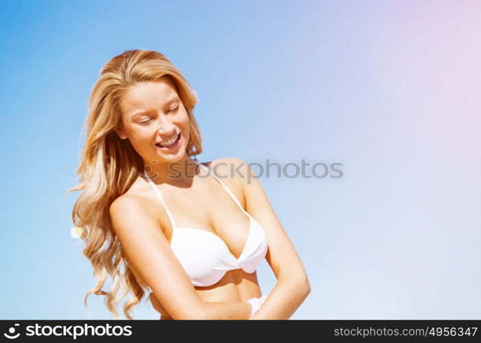 Young woman relaxing on the beach. Portrait of young pretty woman in white bikini relaxing on sandy beach