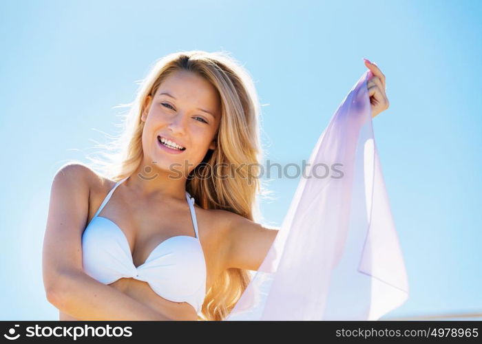 Young woman relaxing on the beach. Portrait of young pretty woman in white bikini relaxing on sandy beach