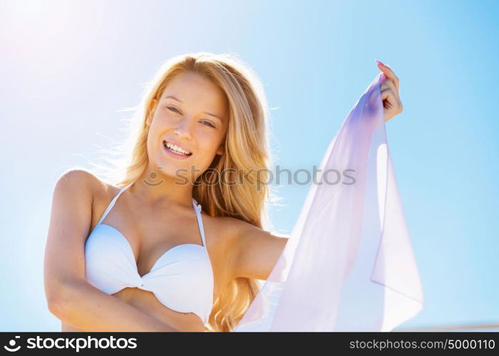 Young woman relaxing on the beach. Portrait of young pretty woman in white bikini relaxing on sandy beach