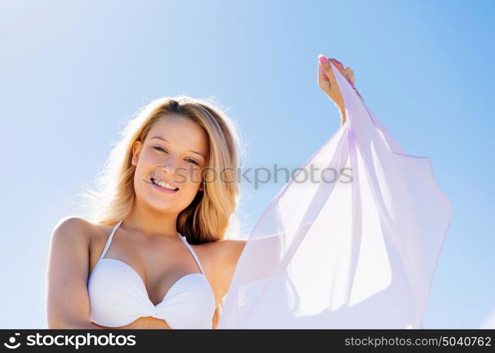 Young woman relaxing on the beach. Portrait of young pretty woman in white bikini relaxing on sandy beach